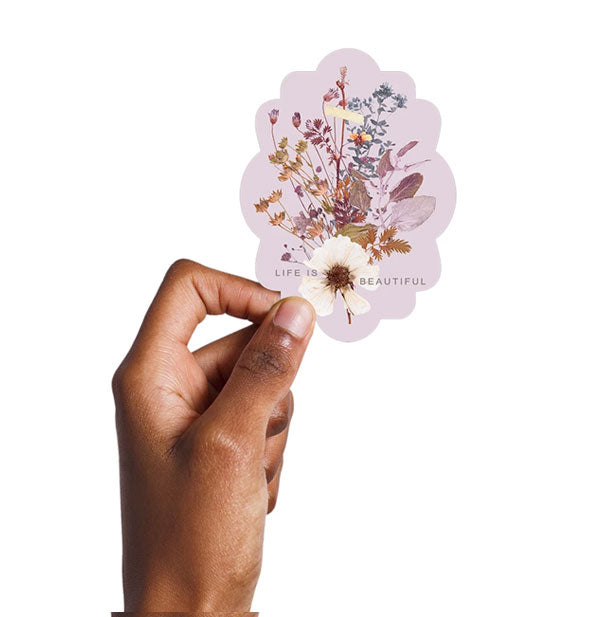 Model's hand holds the Life is Beautiful wildflowers sticker