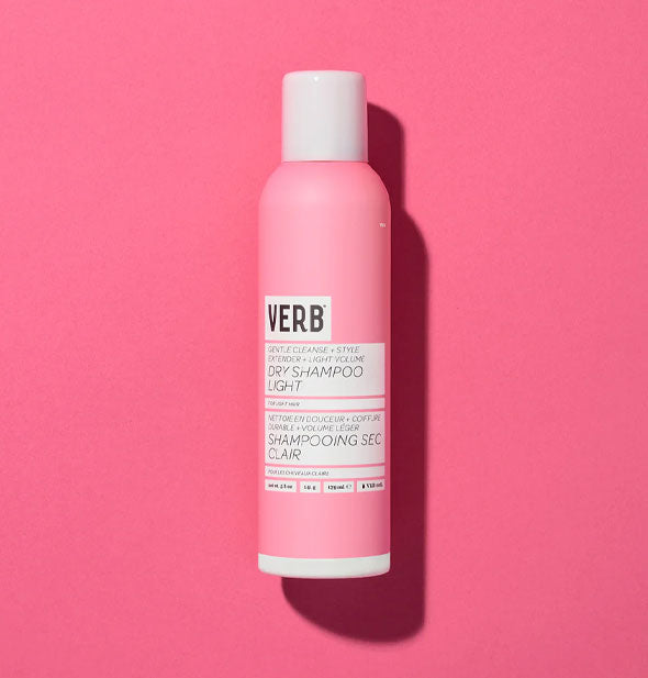 Pink and white can of Verb Dry Shampoo Light with black lettering rests on a pink backdrop