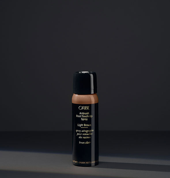 Small can of Oribe Airbrush Root Touch-Up Spray in the shade Light Brown on a dark background