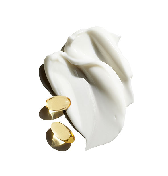 Sample application of white moisturizing cream with two golden oil capsules