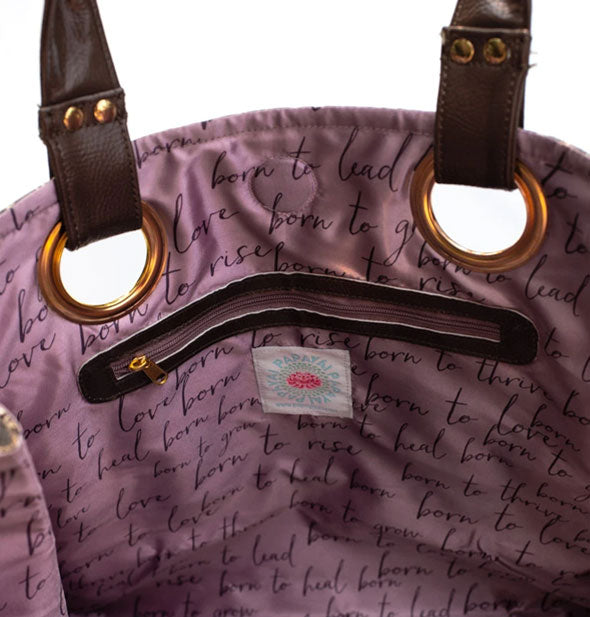 Tote bag interior with purple text-patterned lining, zipper pocket, and gold strap hardware