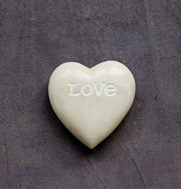 White heart-shaped soapstone is engraved with the word, "Love"