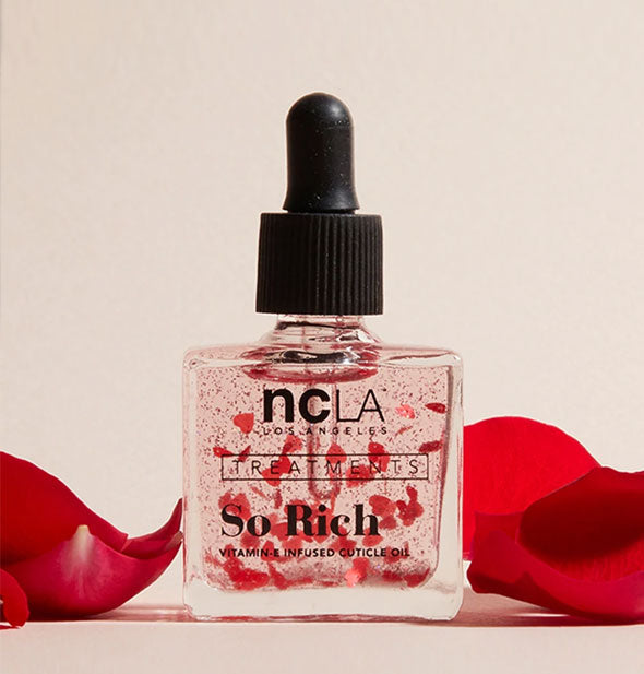 Square glass bottle of NCLA So Rich cuticle oil infused with floating red rose petals
