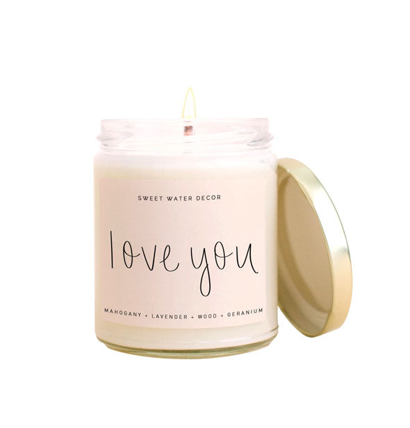 Lit glass jar Sweet Water Decor candle with metal lid and white label that says, "Love you" in black writing