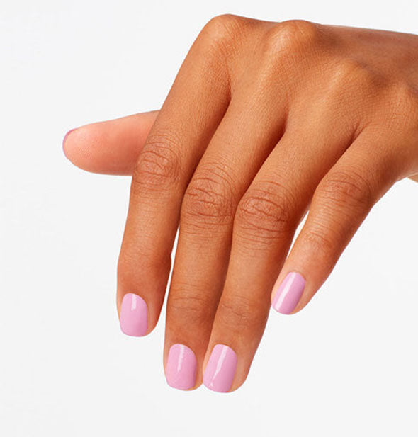 Model's hand wears a pinkish-purple shade of nail polish