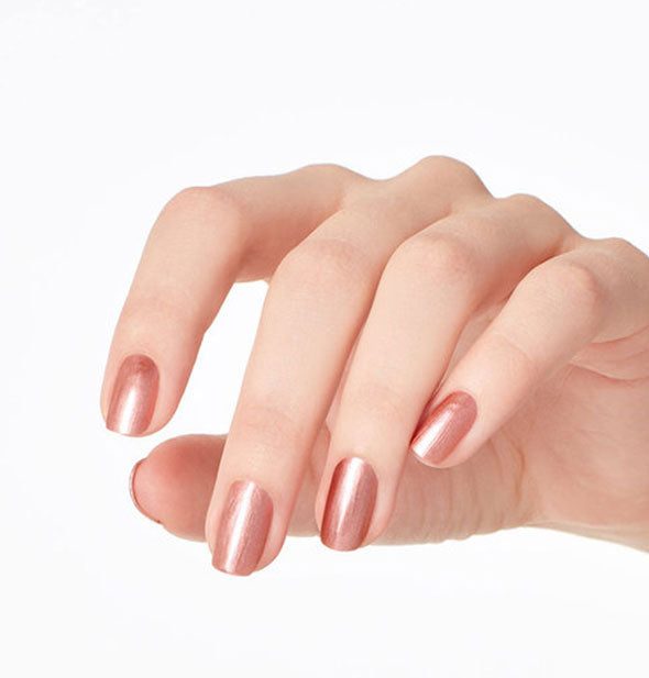 Model's hand wears a shimmery shade of rosy brown nail polish