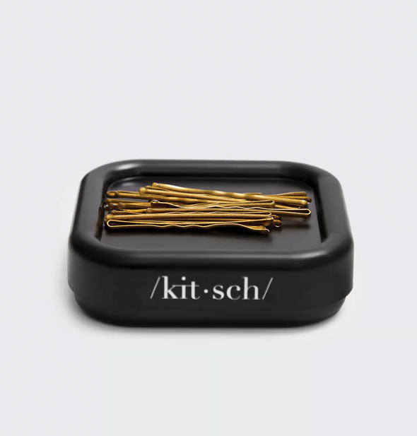 Square black Kitsch brand bobby pin holder with bronze-colored bobby pins on it