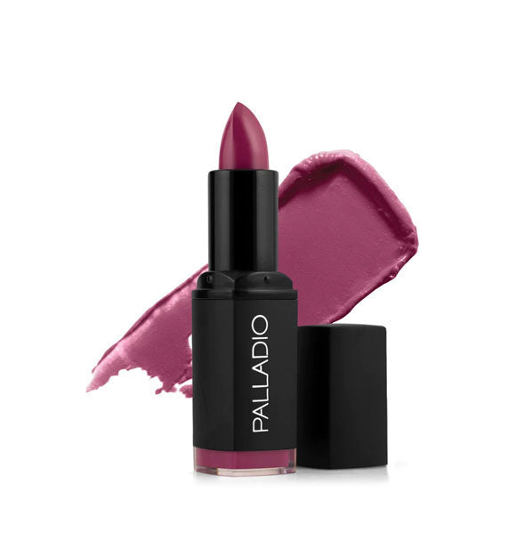 Black tube of Palladio lipstick with cap removed and color swatch behind in a dark pinkish-purple shade called Magnificent Magenta
