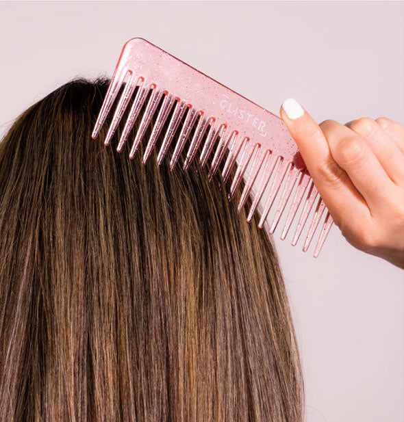 A model combs through their hair with a pink glitter wide-tooth Glister comb
