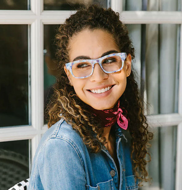 Smiling model wears a pair of light multicolored square reading glasses