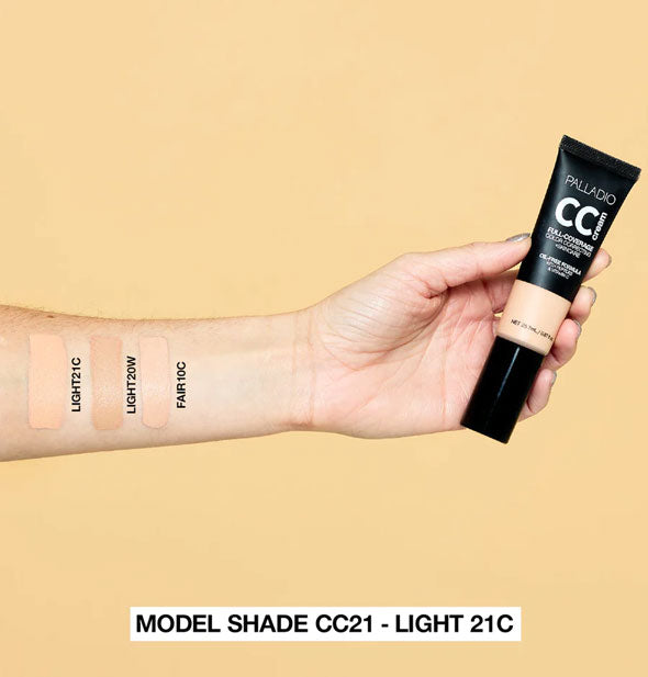 Model's arm wears labeled applications of Light 21C, Light 20W, and Fair 10C Palladio CC Cream shades and holds a tube of product in hand