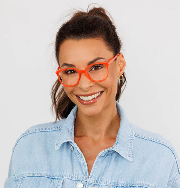 Smiling model wears a pair of bright red-orange glasses