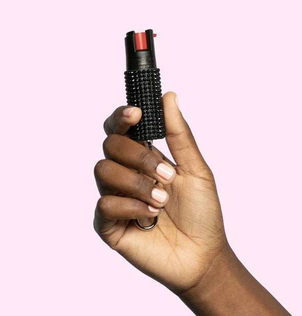 Model's hand holds a black rhinestone-covered pepper spray canister