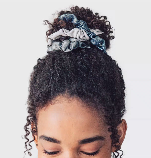 Model wears three metallic hair scrunchies in a bun