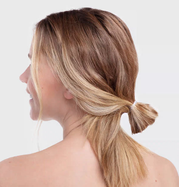 Model wears a small, loose knot in hair secured with an elastic band