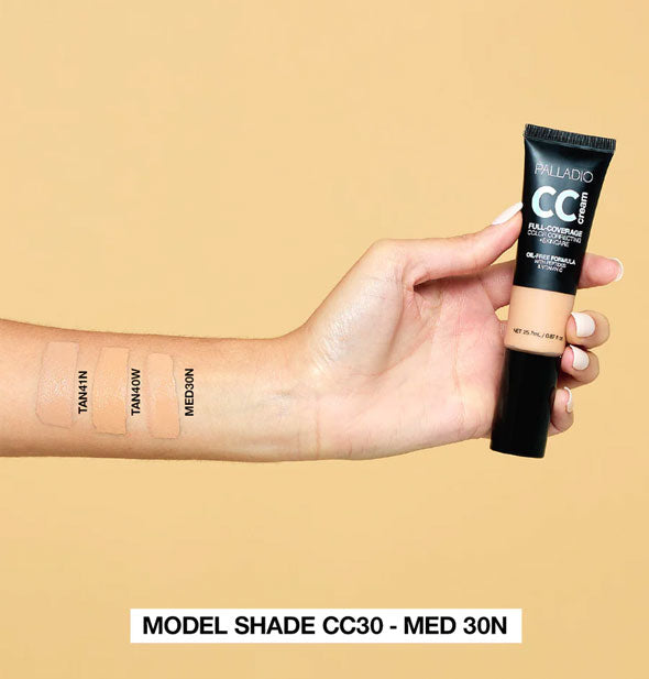 Model's arm wears labeled applications of Tan 41N, Tan 40W, and Med 30N Palladio CC Cream shades and holds a tube of product in hand