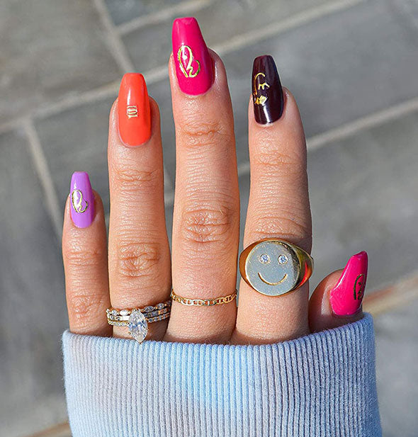 Model wears colorful nails with metallic gold accents