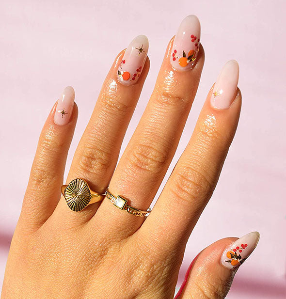 Model wears light pink nails with colorful design accents
