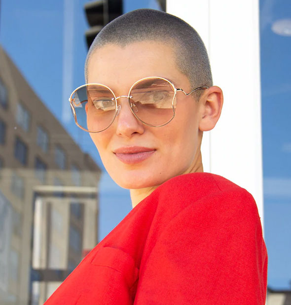 Model wears a rounded pair of large sunglasses with a light lens tint