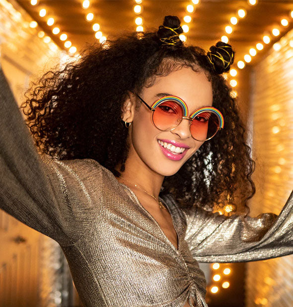 Smiling model wears a pair of round rainbow sunglasses