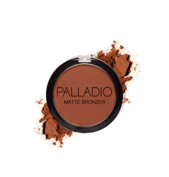 Round compact of pressed Palladio powder bronzer in a dark brown shade with product crushed around it