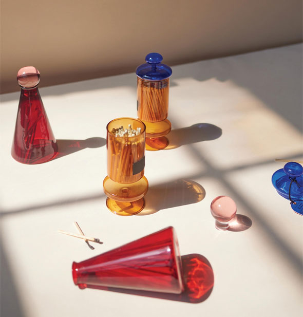 Decorative and colorful glass matchstick bottles and matches on a sunlit surface