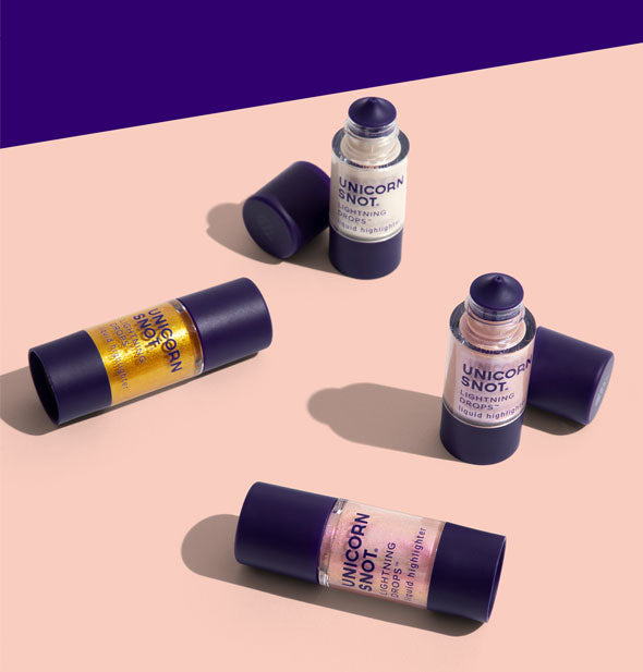 Grouping of four bottles of Unicorn Snot Lightning Drops on a pale peach and dark purple backdrop