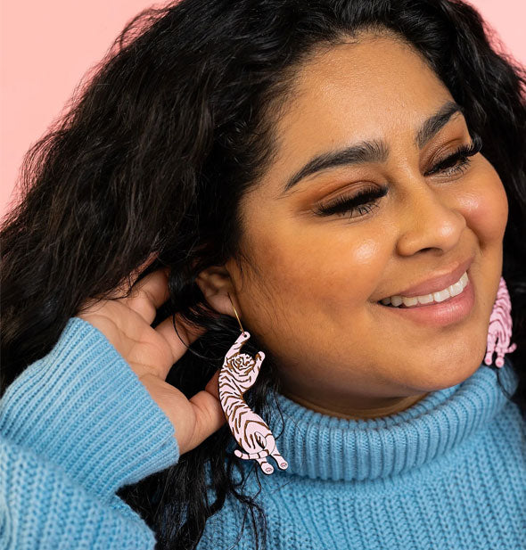 Smiling model wears a pair of pink tiger earrings