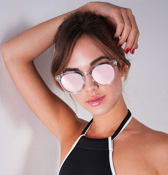 Model wears a pair of rounded reflective sunglasses