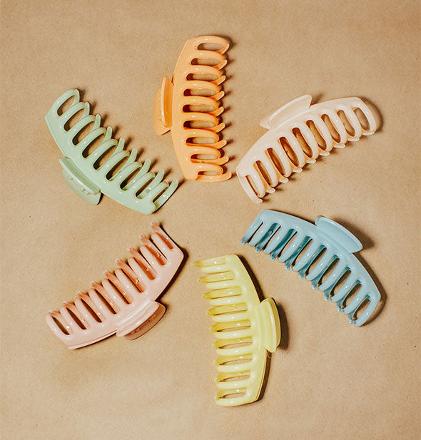 Arrangement of colorful claw clips in a circle on brown background
