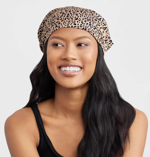 Smiling model wears a leopard print hair scarf in a bandana style
