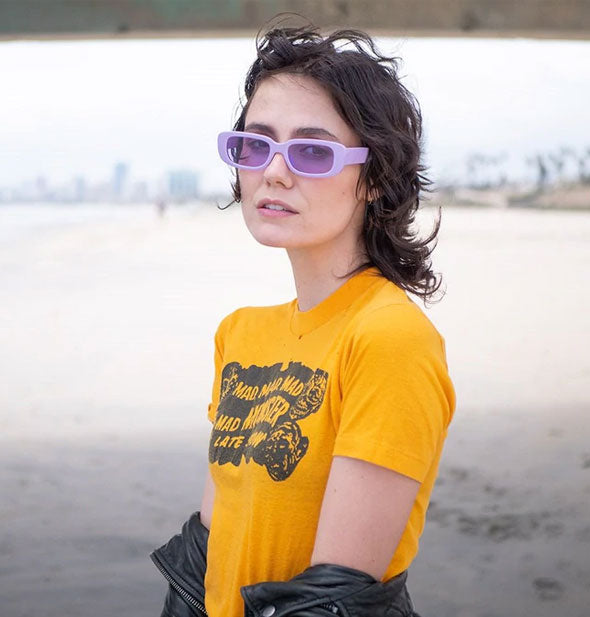 Model wears a purple pair of rectangular sunglasses with purple lenses