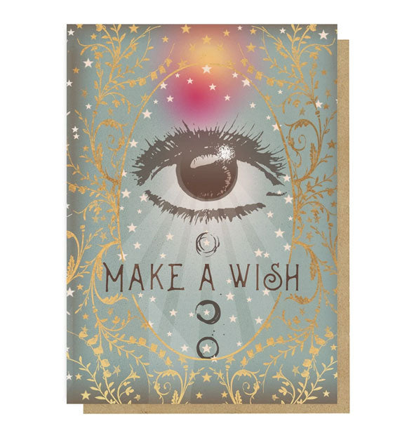Muted green greeting card with kraft envelope behind features metallic gold foil accents, a bold eye illustration, and the words, "Make a Wish"