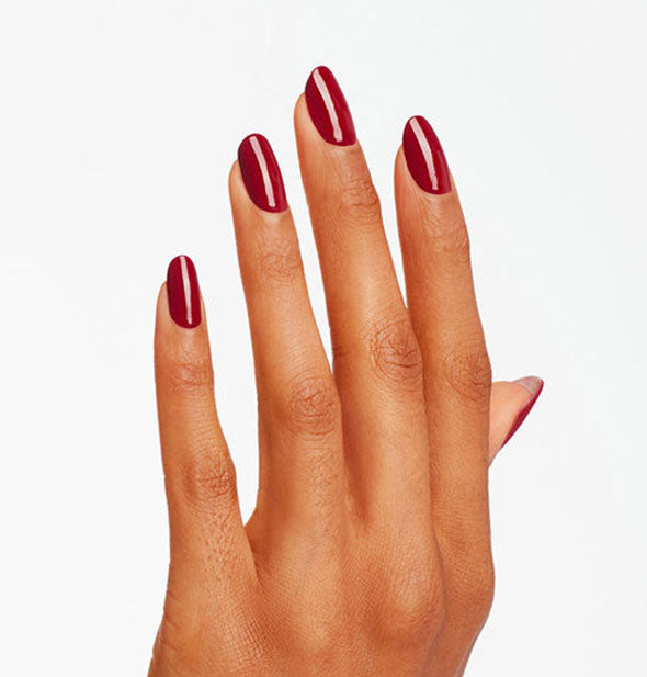 Model's hand wears a dark red shade of nail polish