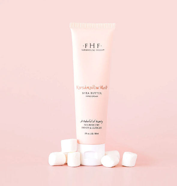 Tube of FarmHouse Fresh Marshmallow Melt Shea Butter Hand Cream is staged with small white marshmallows on a pink background