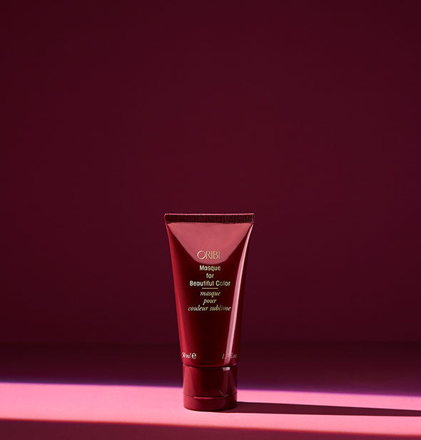 Small bottle of Oribe Masque for Beautiful Color on dark pink background