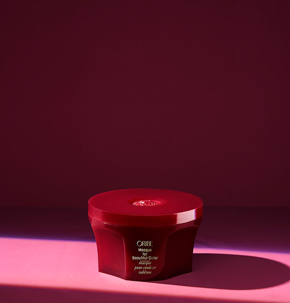 Burgundy pot of Oribe Masque for Beautiful Color on dark pink background