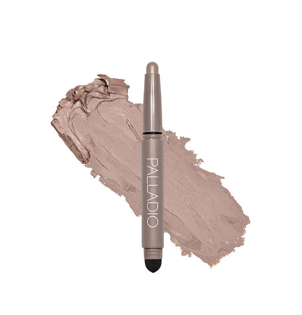 Double-ended Palladio eyeshadow stick with color at one end and black blending sponge at the other rests in front of a color swatch sample in the shade Matte Mocha