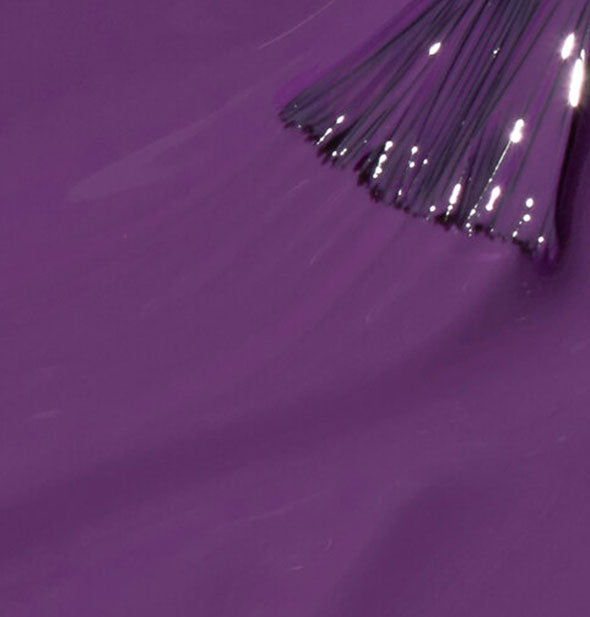A brush tip is drawn through an application of purple nail polish