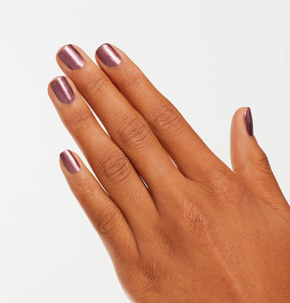 Model's hand wears a shade of shimmer puce nail polish