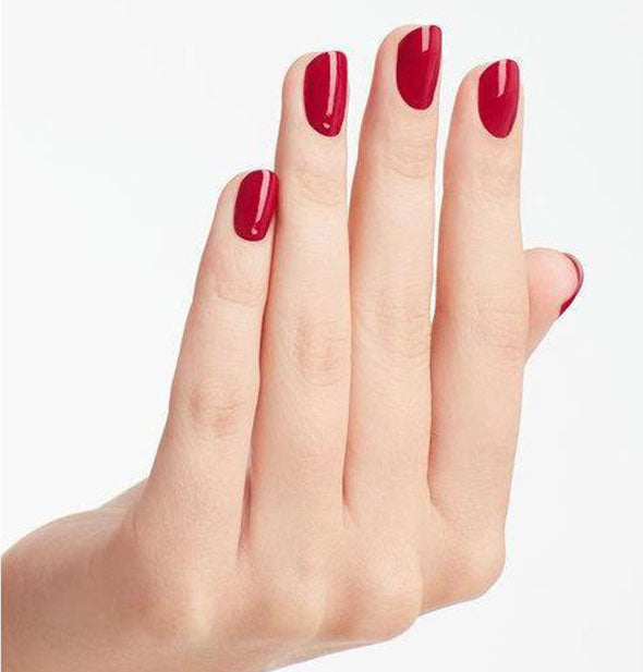 Model's hand wears a deep red shade of nail polish