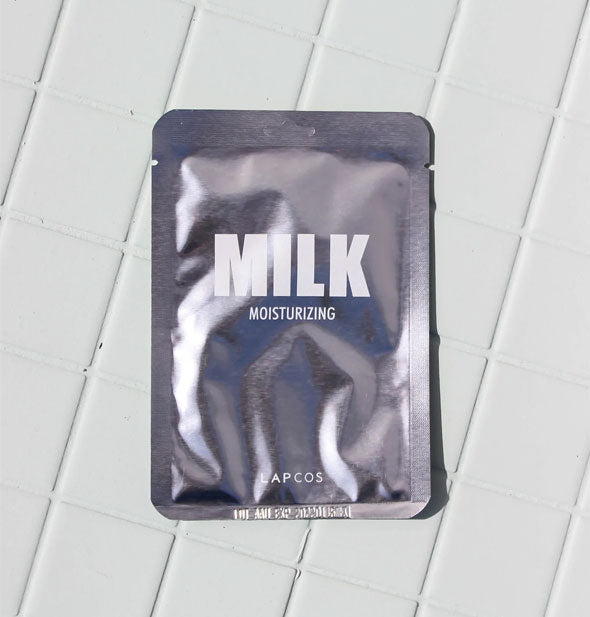 Silver foil Milk Moisturizing sheet mask packet by LAPCOS on white tiled surface