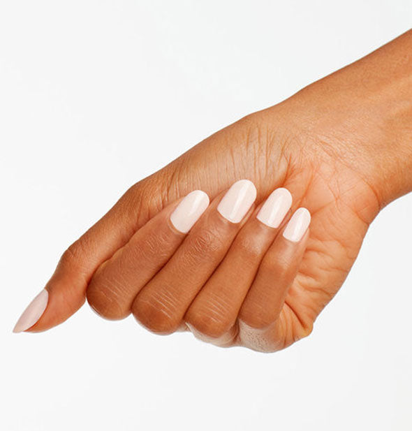 Model's hand wears a whitish-pink shade of nail polish