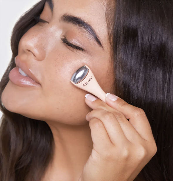 Model demonstrates use of a mini Kitsch facial roller on cheek