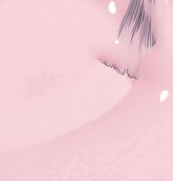 Light purplish-pink nail polish with brush tip dipped into it