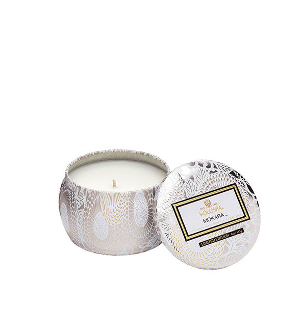 White and gold floral Mokara Voluspa candle tin with matching lid set to the side