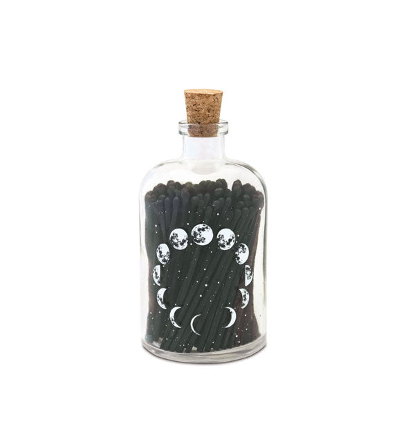 Clear class bottle with cork lid features a white moon phases design and holds black matches inside
