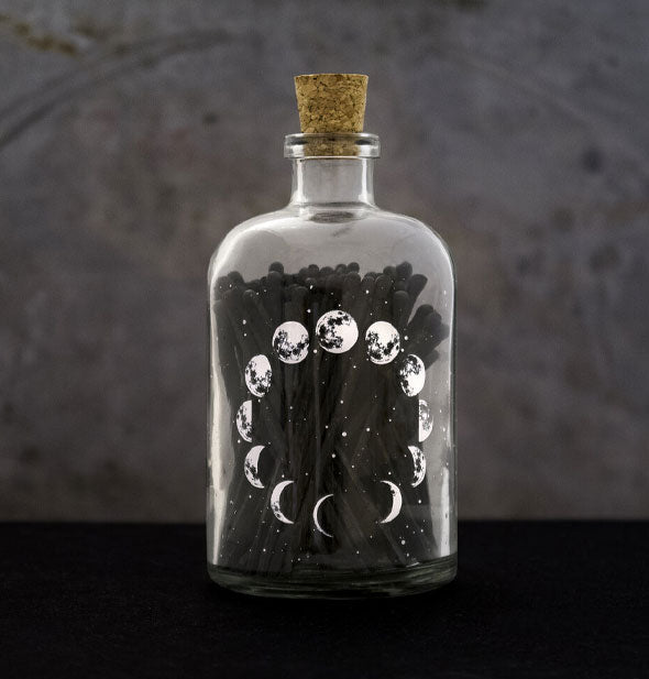Corked glass moon phases match bottle on a dark background
