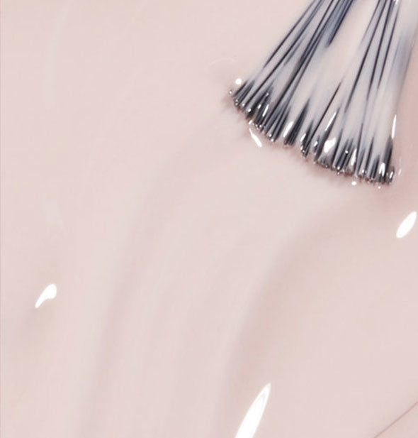 Pinkish off-white nail polish with brush tip drawn through it