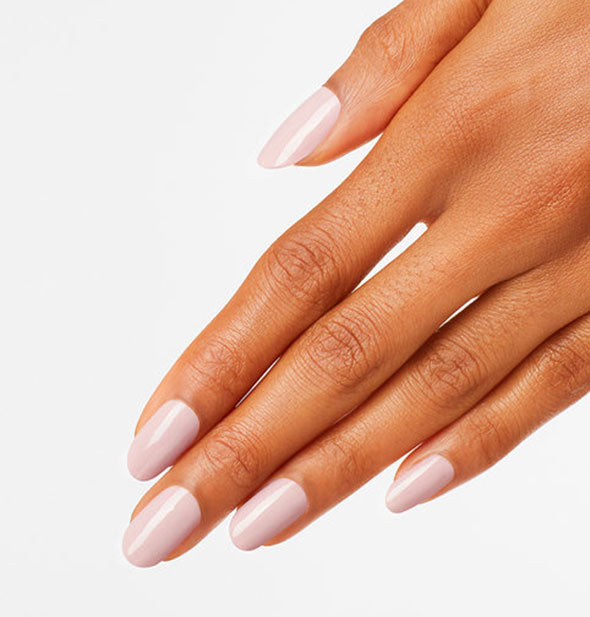 Model's hand wears a light pinkish-white shade of nail polish